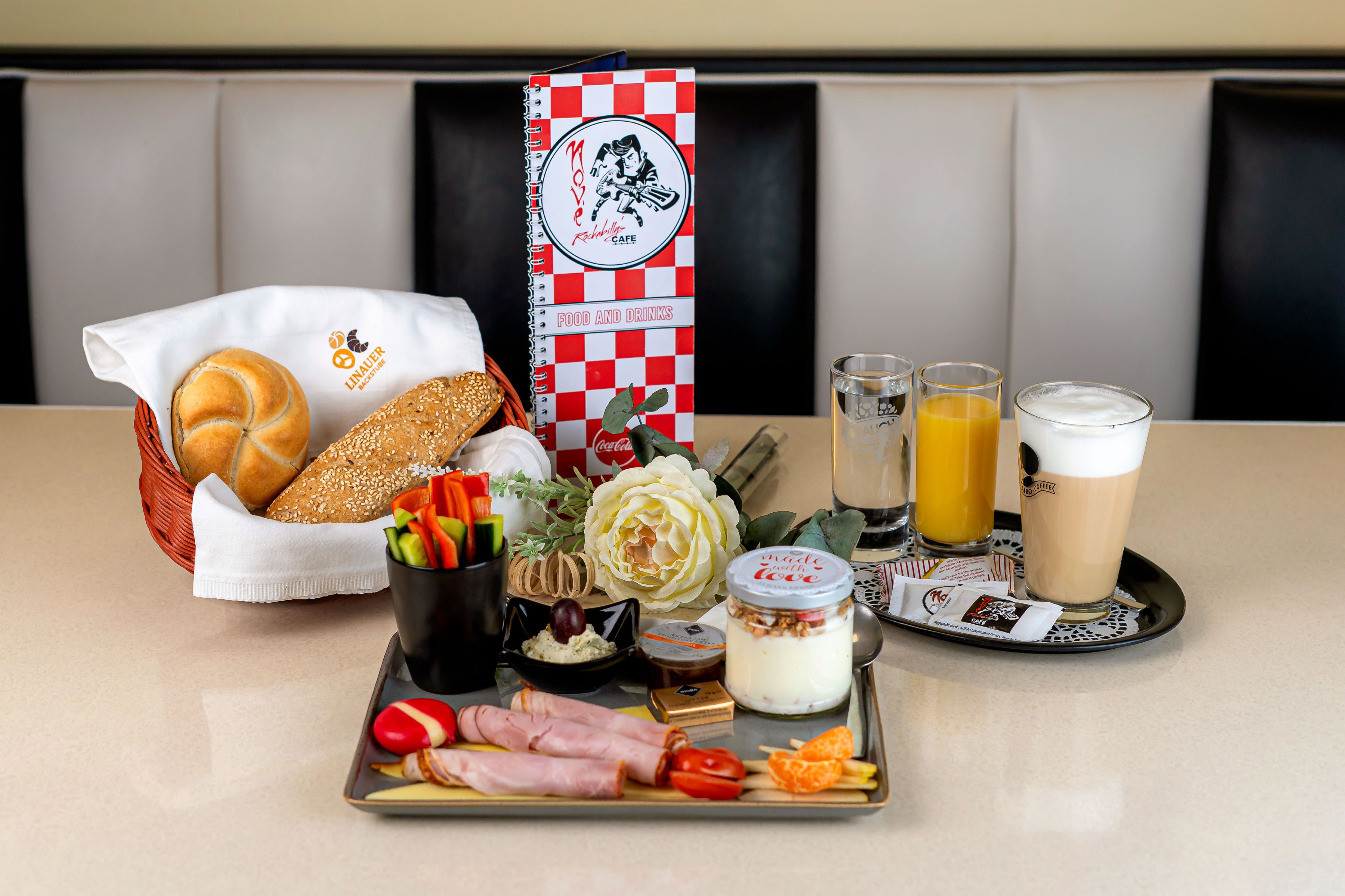 Frühstückstisch im Nové Rockabilly's Cafe mit Brötchen, Aufschnitt, Joghurt, Saft und Kaffee.