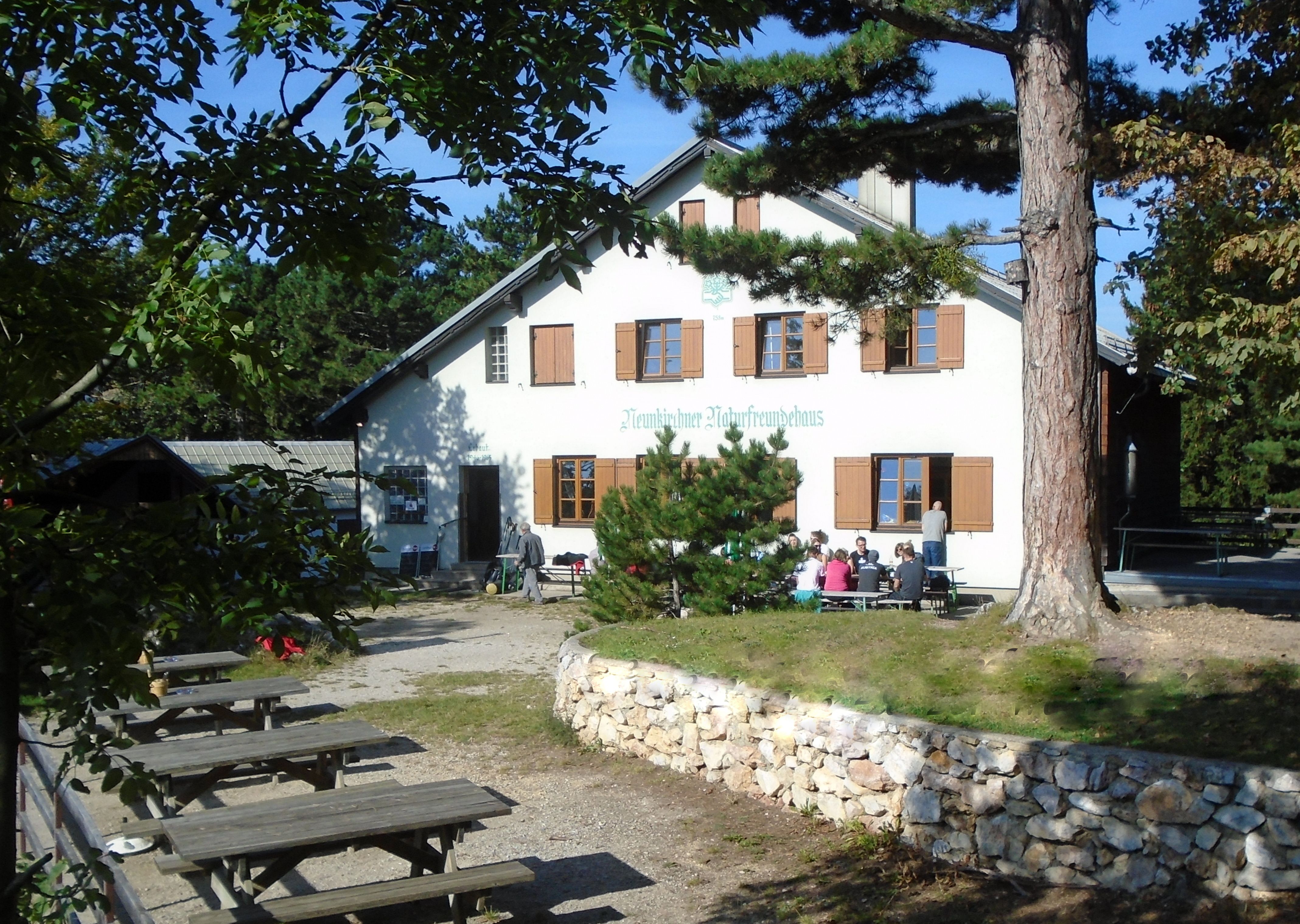 Außenansicht des Neunkirchner Naturfreundehauses mit Sitzgruppen im Freien.