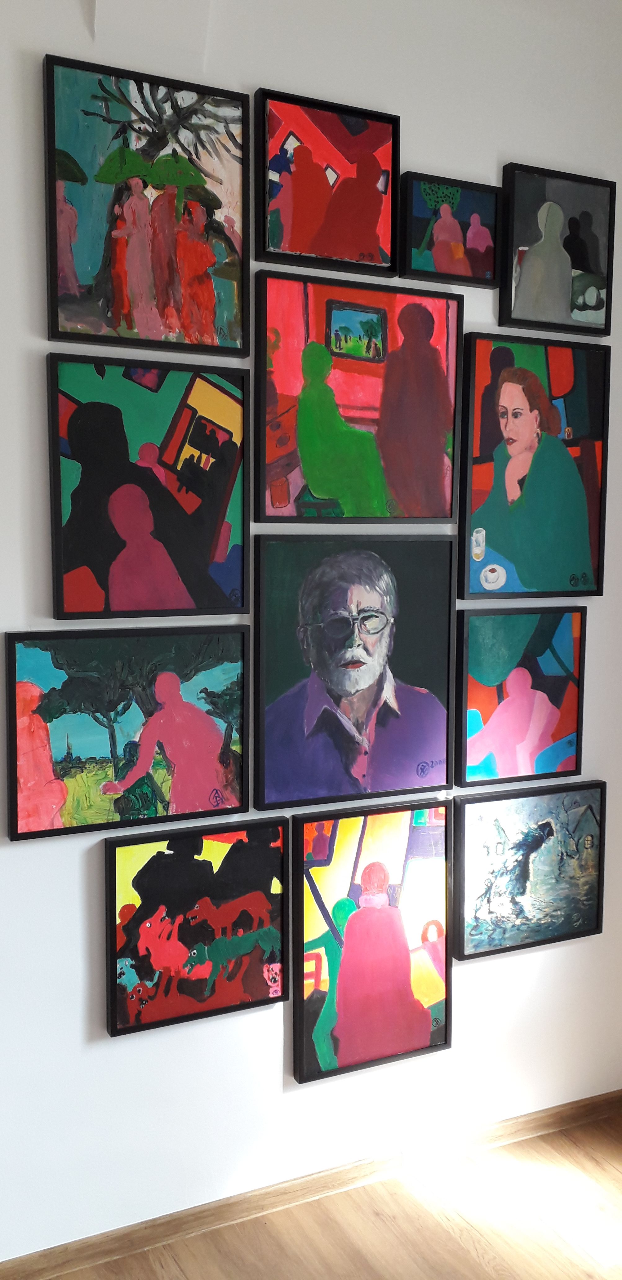 A wall with several colorful paintings in a museum.