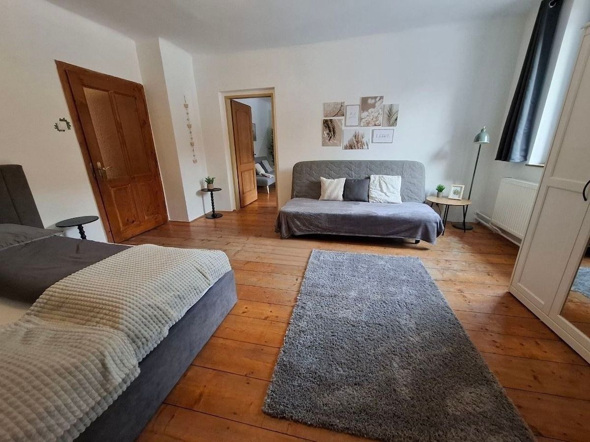 Ein gemütliches Schlafzimmer mit Holzboden, einem Bett, einem Sofa, einem Teppich und Dekorationen an der Wand.
