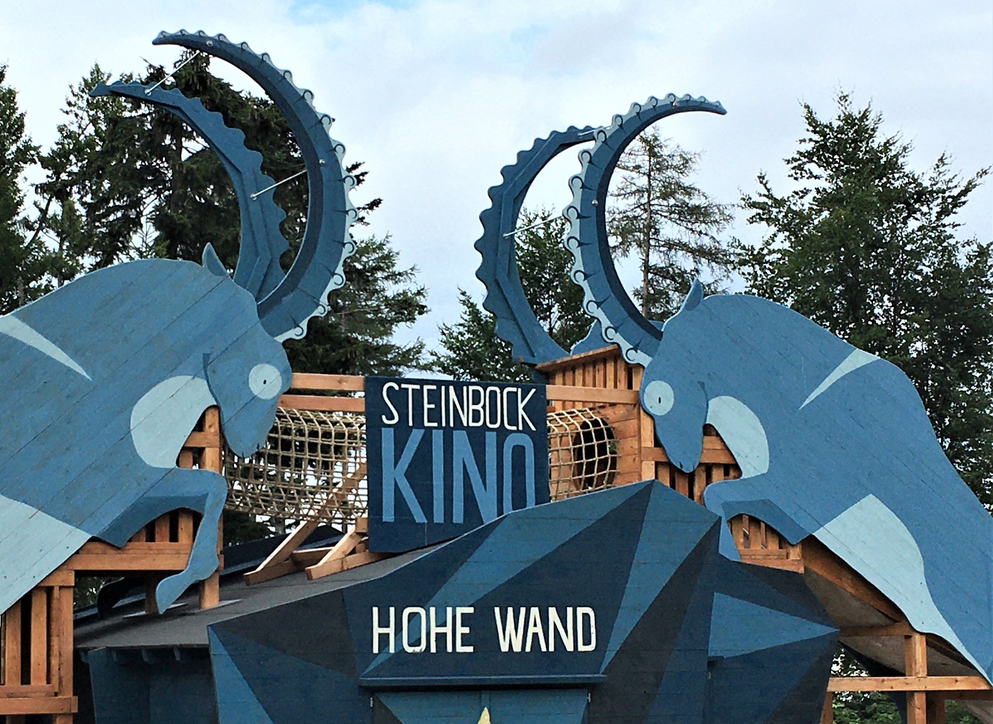 Wooden sculptures of ibexes with the inscription 'Steinbock Kino Hohe Wand'.