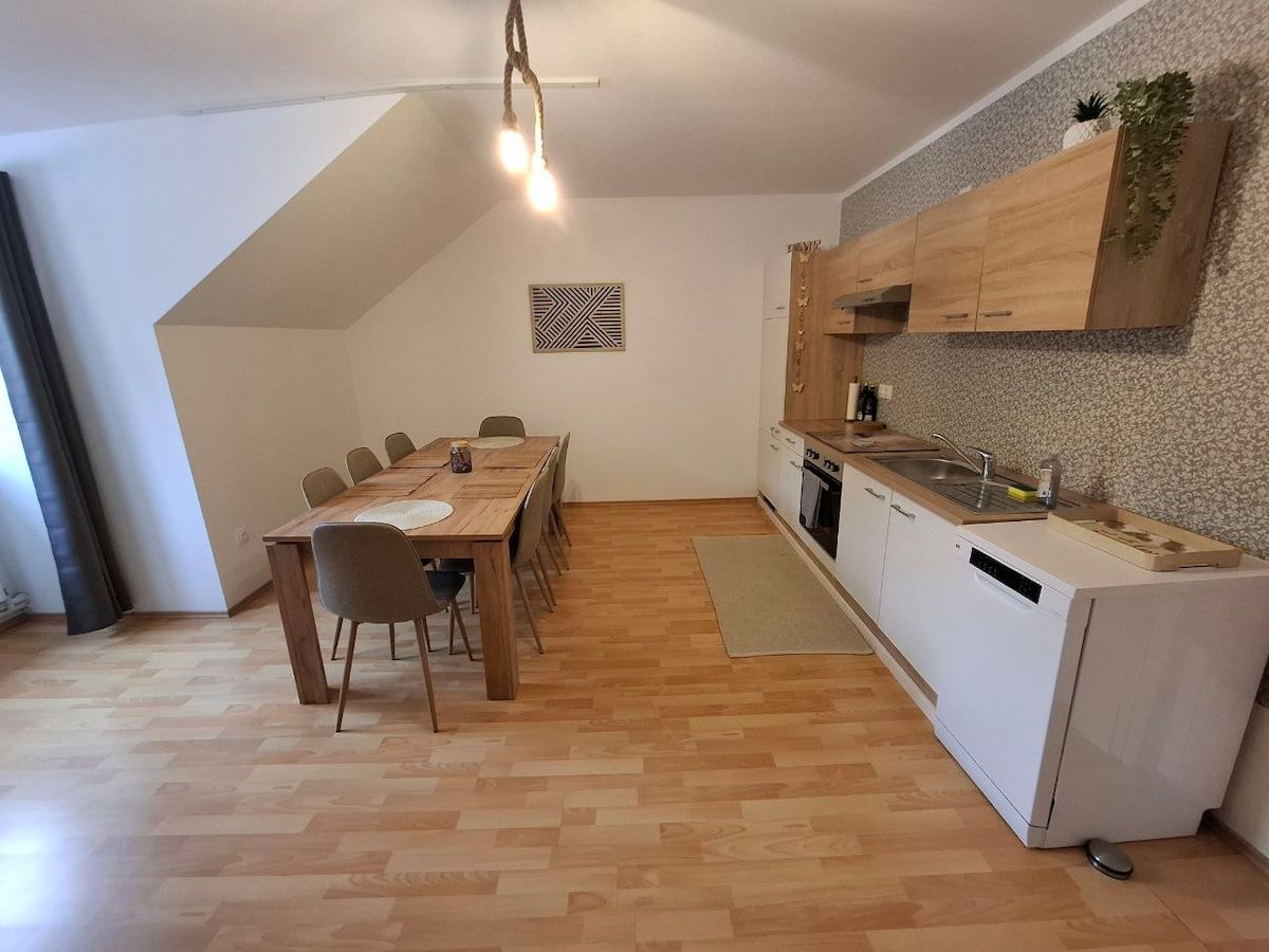 Moderne Küche mit Holzmöbeln und Esstisch in einem hellen Raum.