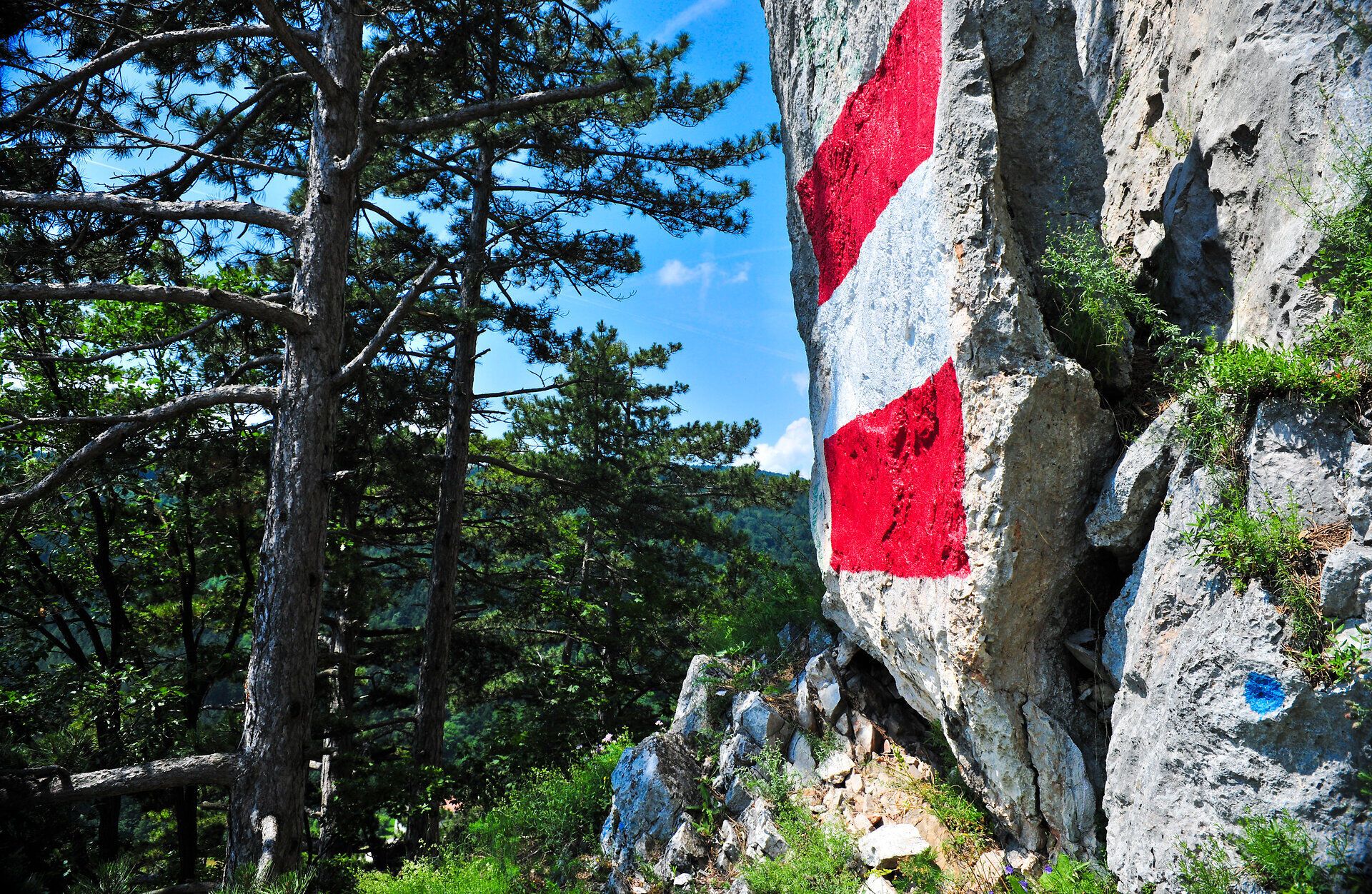 Die majestätischen Felsen erstrahlen in den Farben der Natur, während die Bäume sanft im Sommerwind wiegen. Ein Ort, der zum Verweilen einlädt und die Seele mit seiner unberührten Schönheit erfüllt.