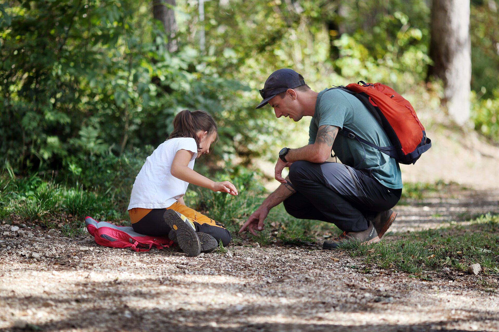 Ein Vater zeigt seiner Tochter etwas Spannendes am Waldboden. 