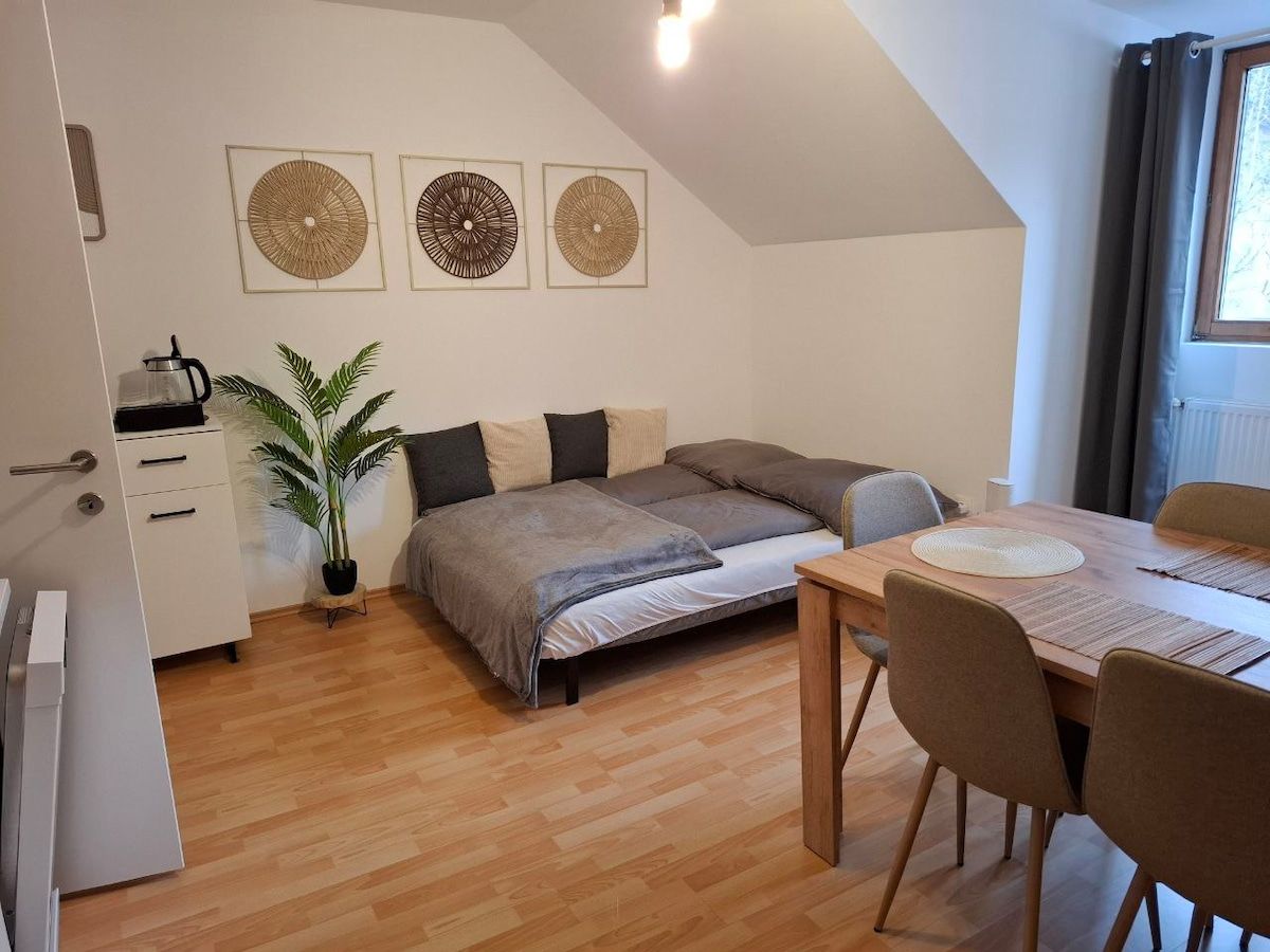 Ein gemütlich eingerichtetes Zimmer mit einem Bett, einem Esstisch und Dekoration an der Wand.