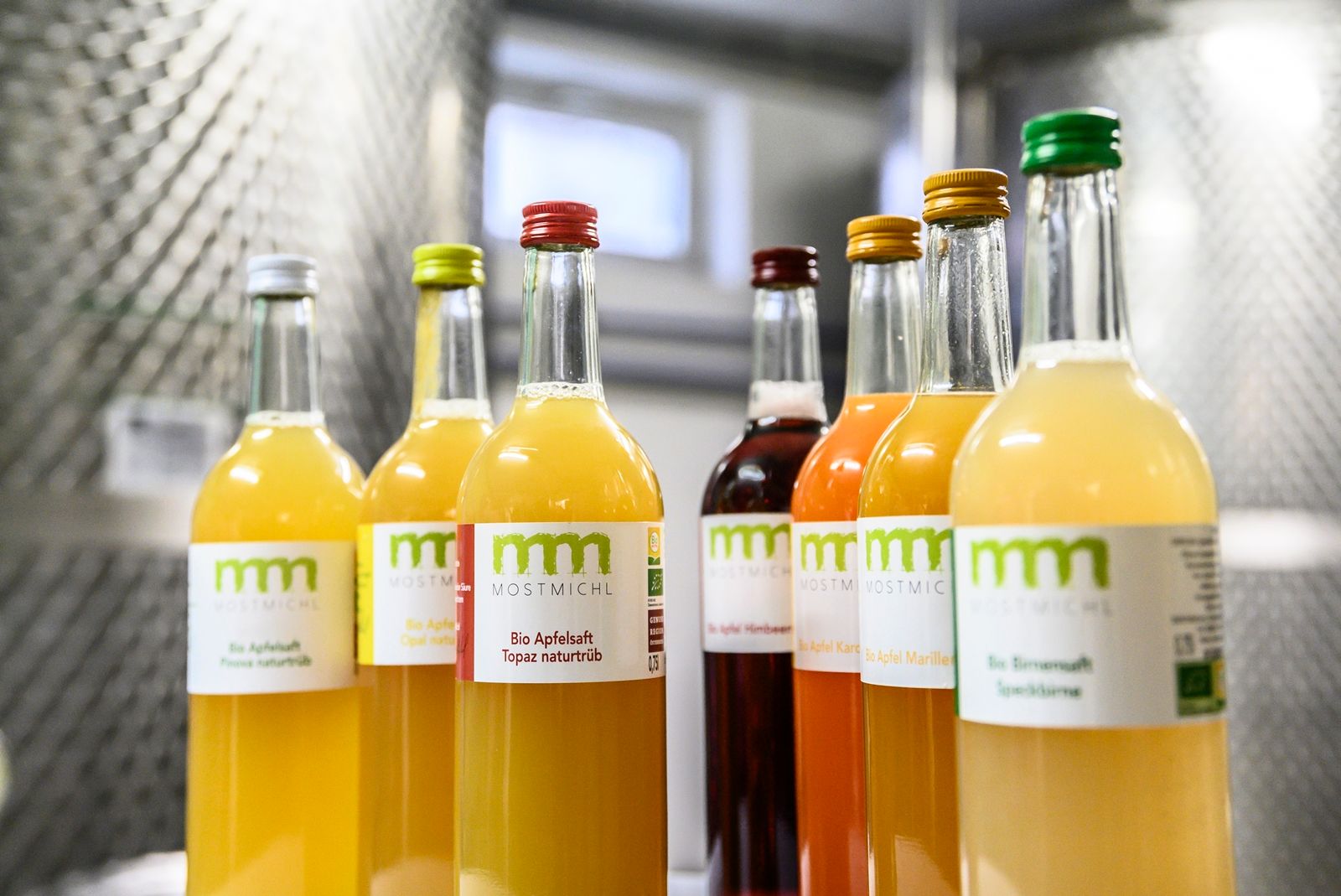 Bottles of various organic juices from MostMichl on a shelf.